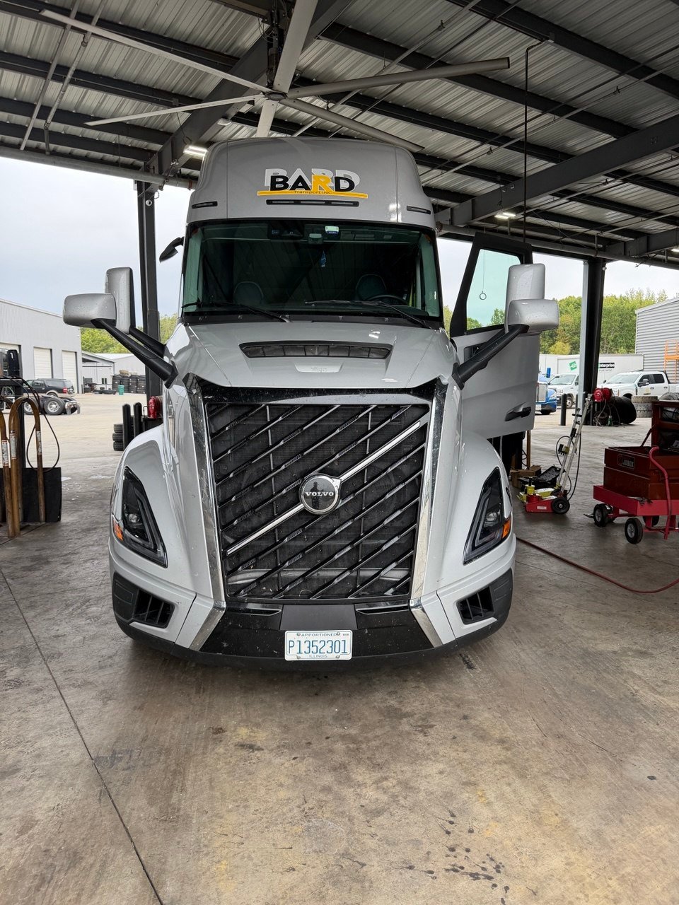 Silver BARD Volvo truck in a service bay with its driver door open